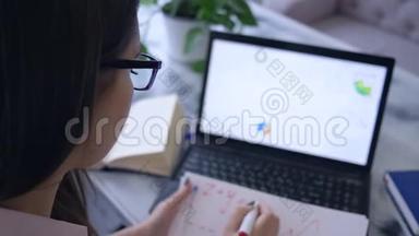 工作项目，女商人使用笔记本电脑，用记号笔在带图表的笔记本上写笔记